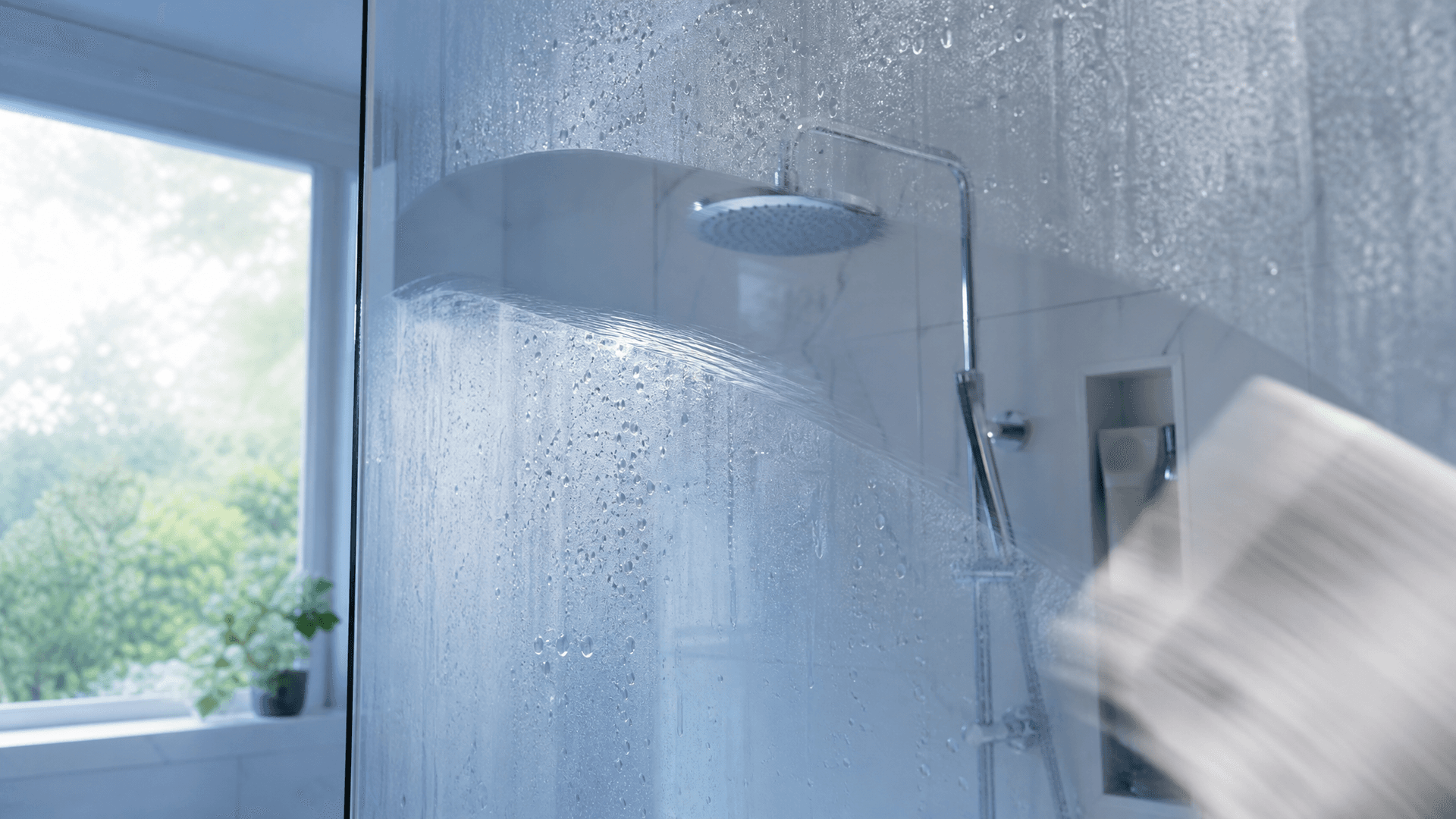 A cloth wiping a foggy limescale shower glass clear in a satisfying reveal